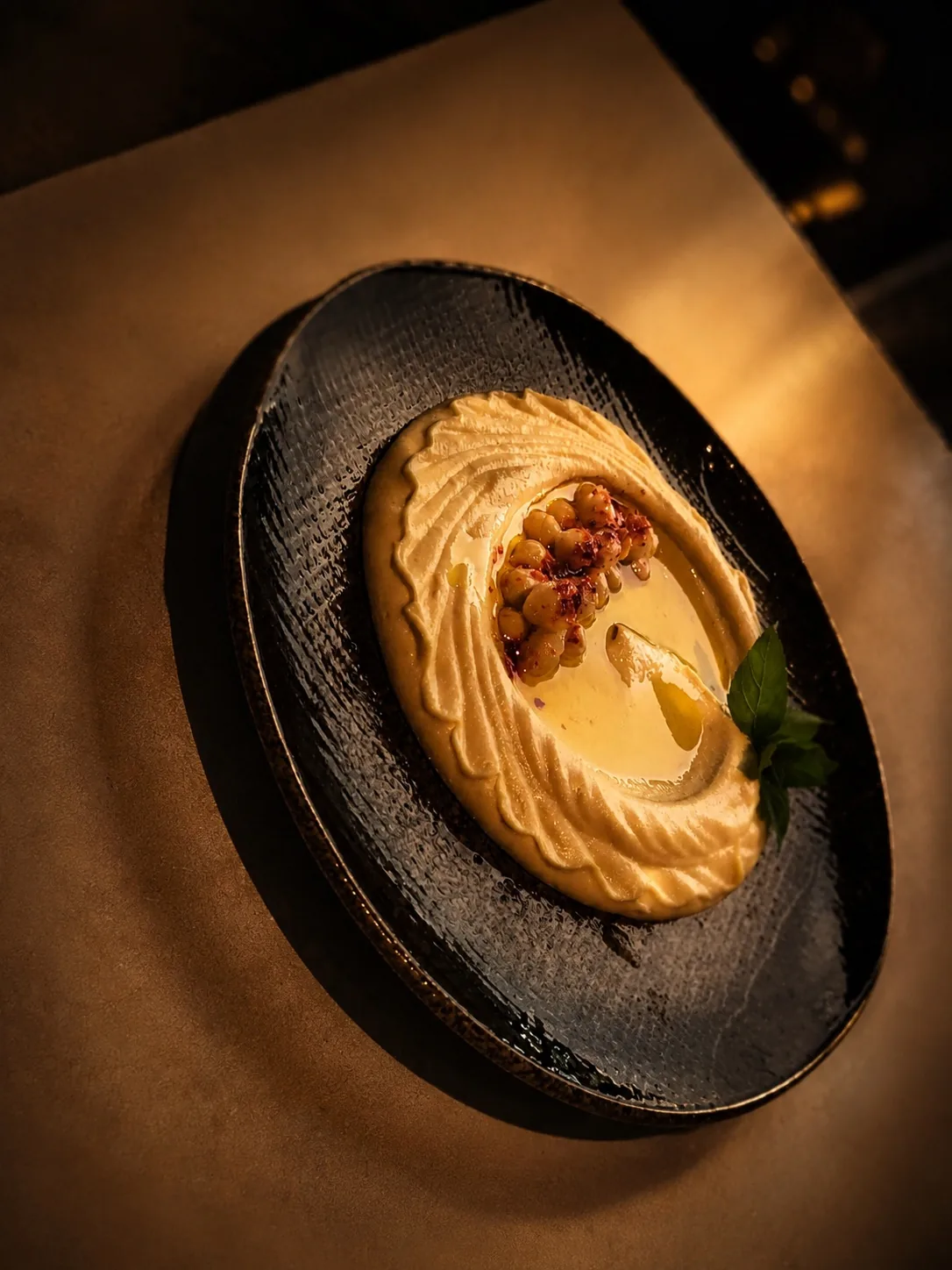 Hommus med kikärtor och olivolja på svart fat